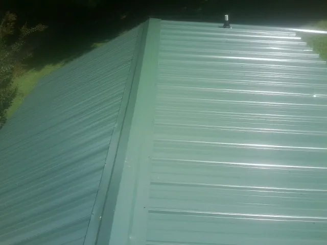 New green metal panels meeting at the ridge of a roof — Flat Roof Repair work by our crew in Adamstown